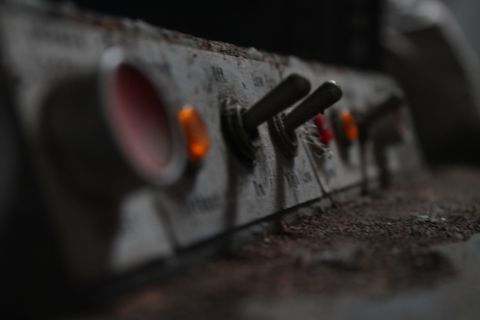 An extreme close up shot of the switches and buttons of a dusty old control panel.